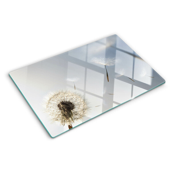 Tagliere in vetro con motivo di denti di leone sullo sfondo di una finestra