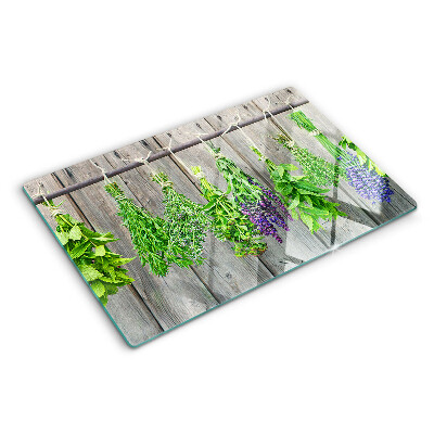 Tagliere in vetro con stampa di erbe essiccate su sfondo di legno