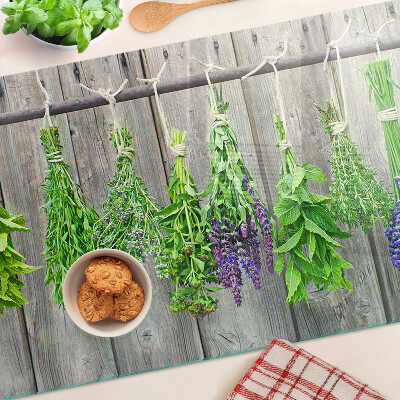 Tagliere in vetro con stampa di erbe essiccate su sfondo di legno