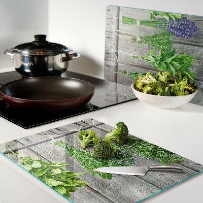 Tagliere in vetro con stampa di erbe essiccate su sfondo di legno