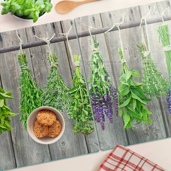 Tagliere in vetro con stampa di erbe essiccate su sfondo di legno