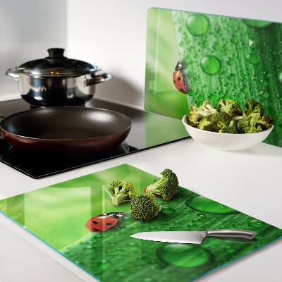 Tagliere in vetro temperato con motivo di coccinelle su sfondo verde