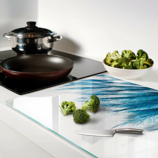 Tagliere in vetro con motivo di piume blu su sfondo bianco