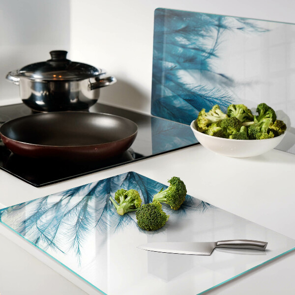 Tagliere in vetro con motivo di piume blu su sfondo bianco