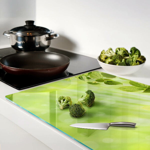 Tagliere in vetro con motivo di foglie verdi su sfondo chiaro