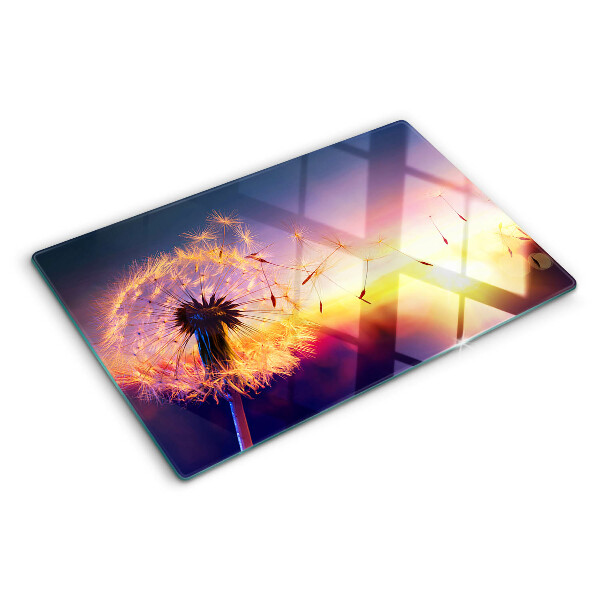 Tagliere in vetro temperato con motivo di denti di leone sullo sfondo di un tramonto