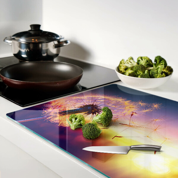 Tagliere in vetro temperato con motivo di denti di leone sullo sfondo di un tramonto