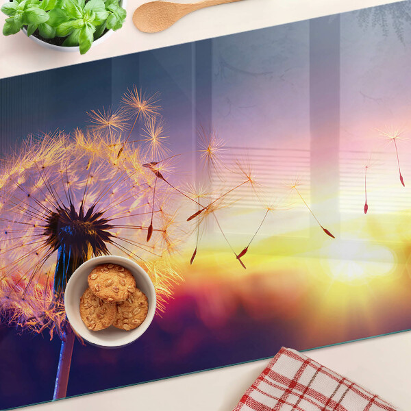 Tagliere in vetro temperato con motivo di denti di leone sullo sfondo di un tramonto