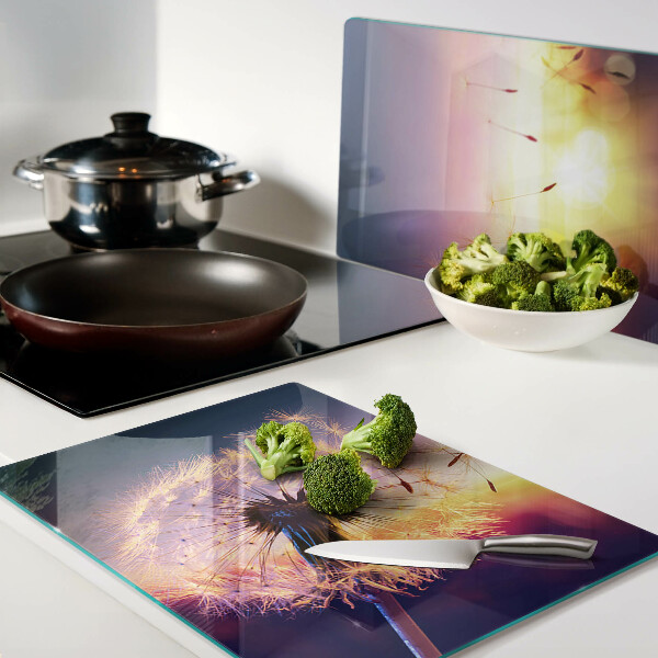 Tagliere in vetro temperato con motivo di denti di leone sullo sfondo di un tramonto