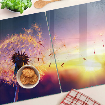 Tagliere in vetro temperato con motivo di denti di leone sullo sfondo di un tramonto