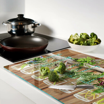 Tagliere in vetro temperato con motivo di erbe in barattoli su sfondo di legno