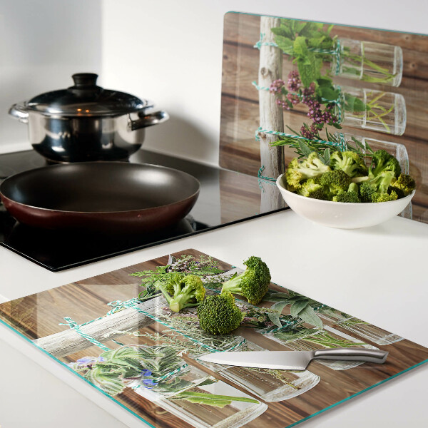 Tagliere in vetro temperato con motivo di erbe in barattoli su sfondo di legno