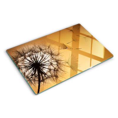 Tagliere in vetro temperato con motivo di denti di leone sullo sfondo di un tramonto