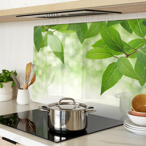 Tagliere in vetro temperato con motivo di foglie su sfondo verde sfocato