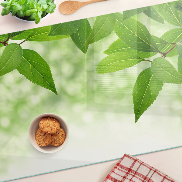 Tagliere in vetro temperato con motivo di foglie su sfondo verde sfocato