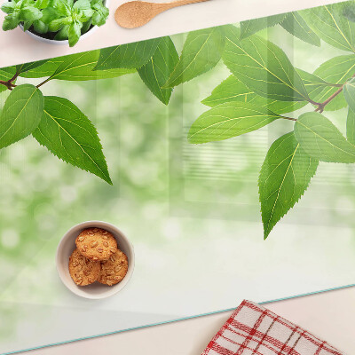 Tagliere in vetro temperato con motivo di foglie su sfondo verde sfocato