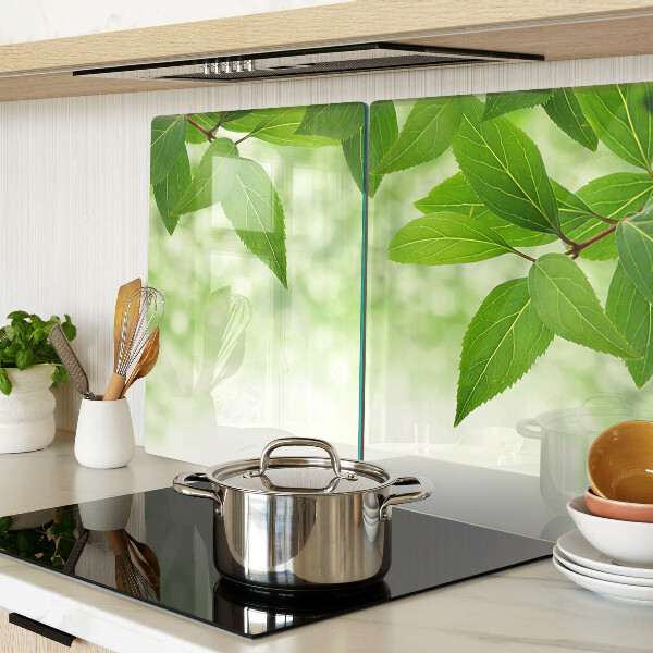 Tagliere in vetro temperato con motivo di foglie su sfondo verde sfocato