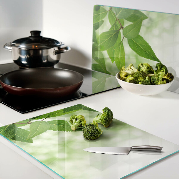 Tagliere in vetro temperato con motivo di foglie su sfondo verde sfocato