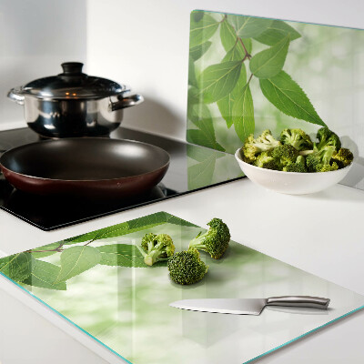 Tagliere in vetro temperato con motivo di foglie su sfondo verde sfocato