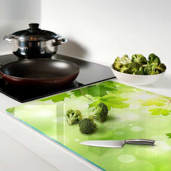 Tagliere in vetro temperato con motivo di foglie illuminate dai raggi del sole