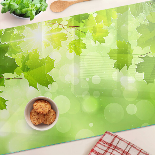 Tagliere in vetro temperato con motivo di foglie illuminate dai raggi del sole