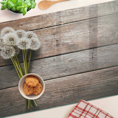 Tagliere in vetro temperato con motivo di fiori e soffioni su sfondo legno