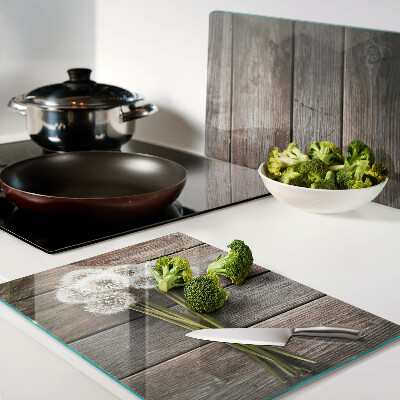 Tagliere in vetro temperato con motivo di fiori e soffioni su sfondo legno