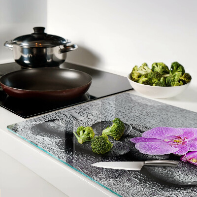 Tagliere in vetro temperato con motivo di fiori e pietre sullo sfondo dell'acqua