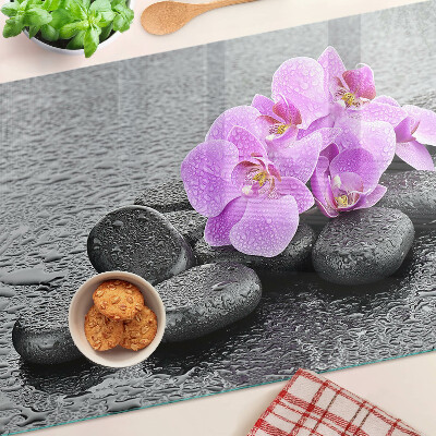 Tagliere in vetro temperato con motivo di fiori e pietre sullo sfondo dell'acqua