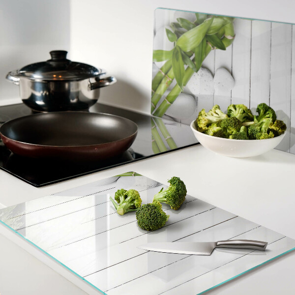 Tagliere in vetro temperato con motivo di bamboo e pietre su sfondo di legno