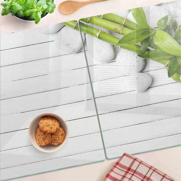 Tagliere in vetro temperato con motivo di bamboo e pietre su sfondo di legno
