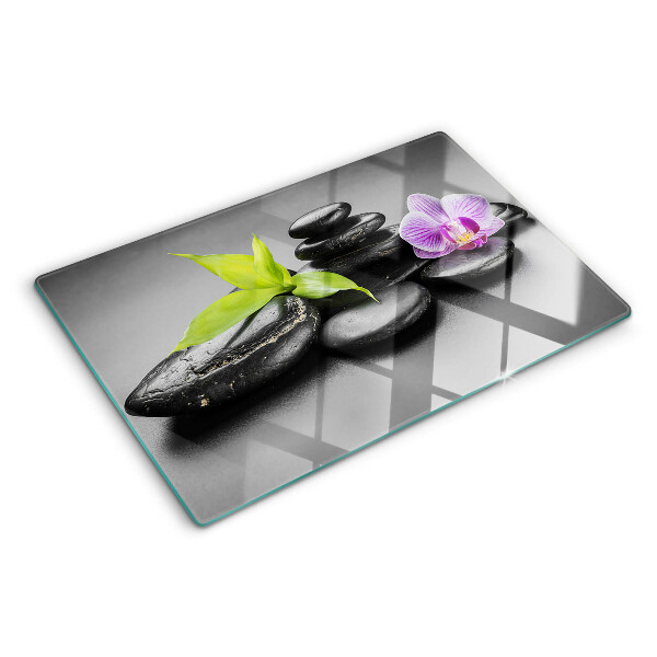 Tagliere in vetro con motivo di pietre e orchidea sullo sfondo