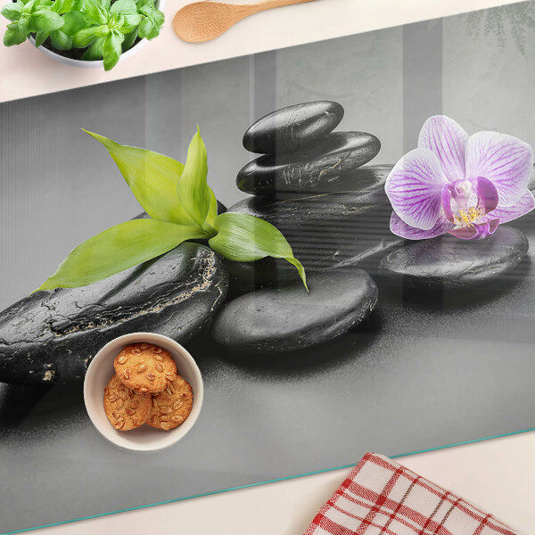 Tagliere in vetro con motivo di pietre e orchidea sullo sfondo