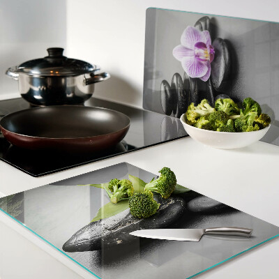 Tagliere in vetro con motivo di pietre e orchidea sullo sfondo