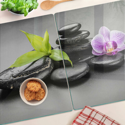 Tagliere in vetro con motivo di pietre e orchidea sullo sfondo