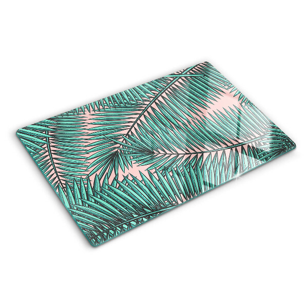 Tagliere in vetro con decorazione di foglie di palma su sfondo rosa