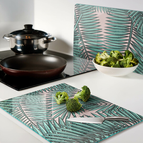 Tagliere in vetro con decorazione di foglie di palma su sfondo rosa