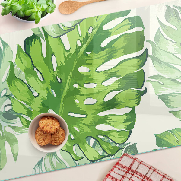 Tagliere in vetro temperato con motivo di foglie di monstera su sfondo chiaro