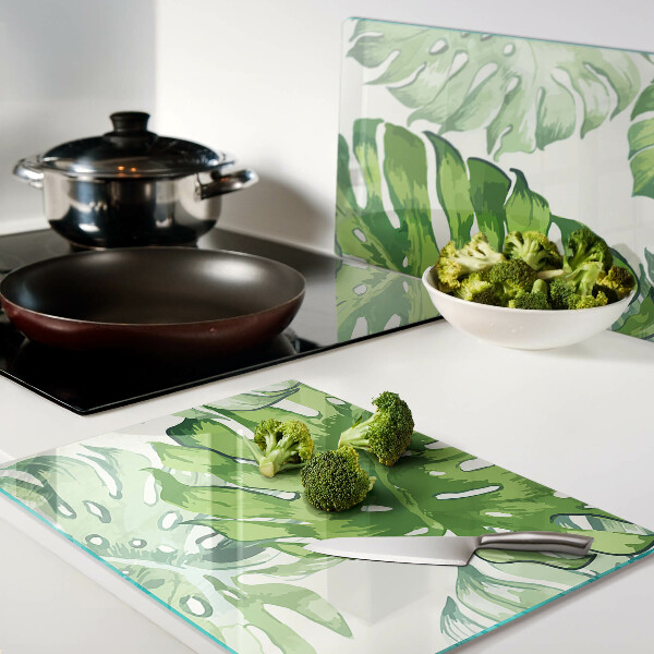 Tagliere in vetro temperato con motivo di foglie di monstera su sfondo chiaro