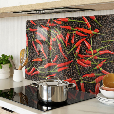 Tagliere in vetro con decorazione di peperoncini su sfondo effetto pepe nero