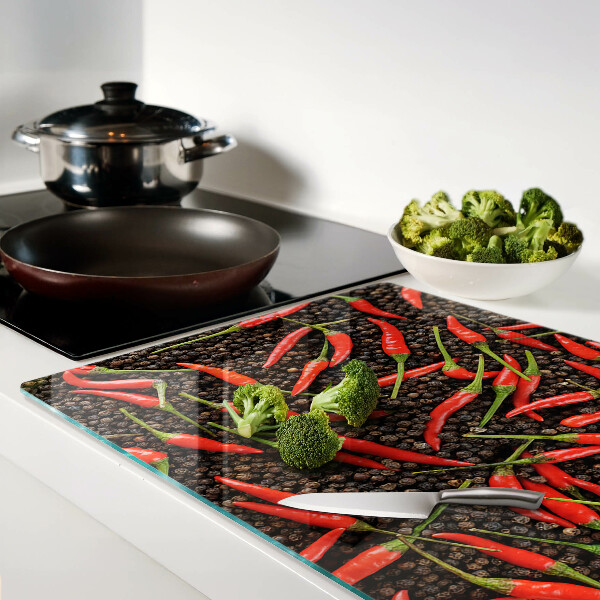 Tagliere in vetro con decorazione di peperoncini su sfondo effetto pepe nero