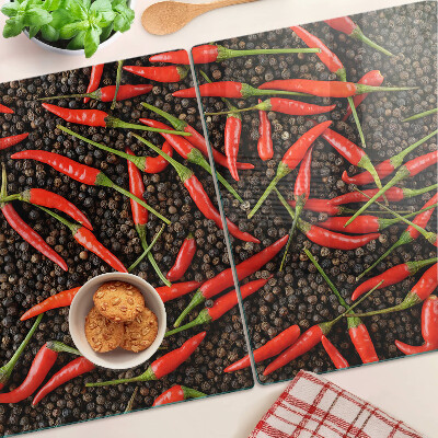 Tagliere in vetro con decorazione di peperoncini su sfondo effetto pepe nero