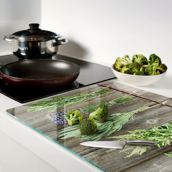 Tagliere in vetro con stampa di erbe su sfondo di legno