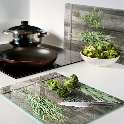 Tagliere in vetro con stampa di erbe su sfondo di legno