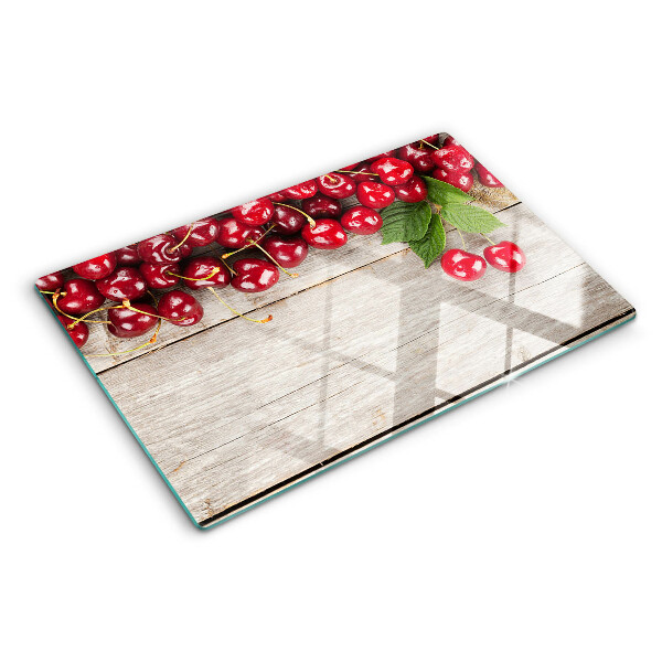 Tagliere in vetro con stampa di ciliegie su sfondo di legno