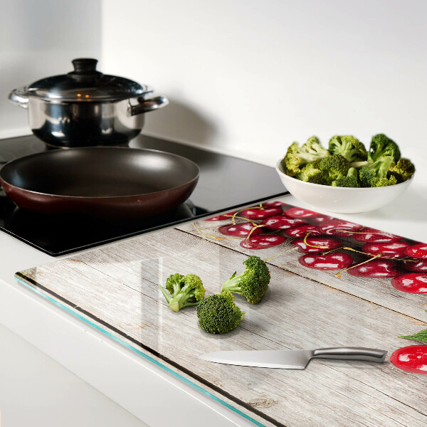 Tagliere in vetro con stampa di ciliegie su sfondo di legno