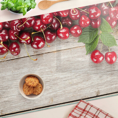 Tagliere in vetro con stampa di ciliegie su sfondo di legno