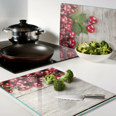 Tagliere in vetro con stampa di ciliegie su sfondo di legno