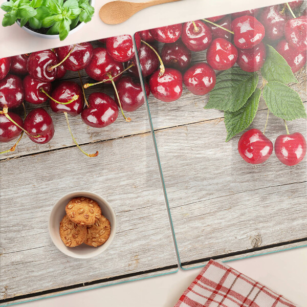 Tagliere in vetro con stampa di ciliegie su sfondo di legno