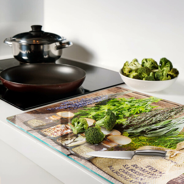 Tagliere in vetro con stampa di erbe e spezie su sfondo di legno